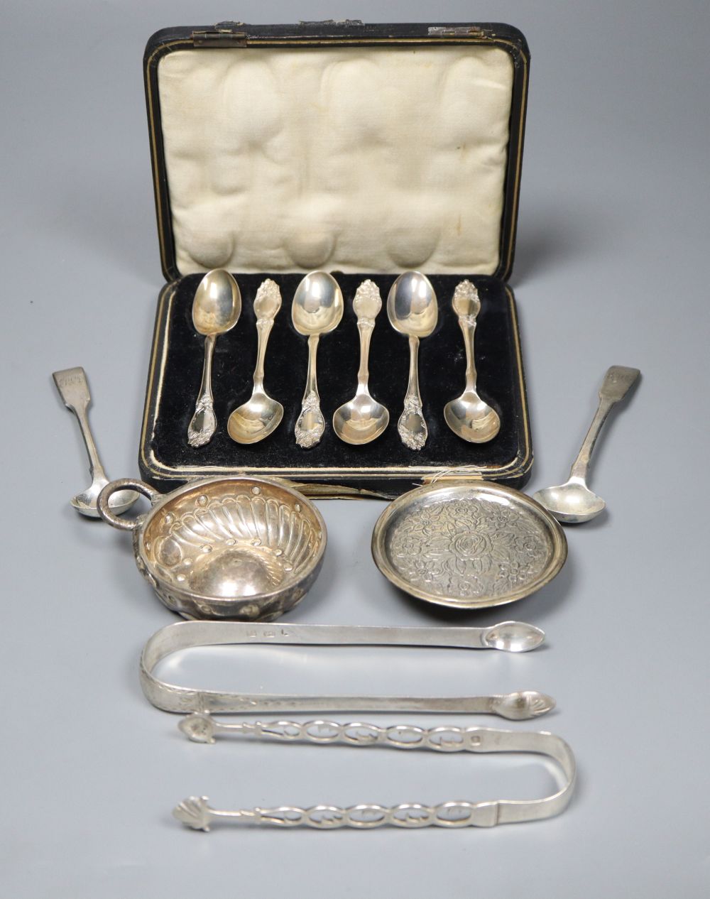 A cased set of six silver teaspoons spoons, two pairs of tongs, paten dish and three other items.